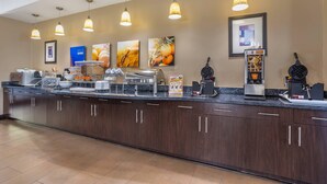 Zona de recepción de hotel con una larga barra de mostrador, varios dispensadores de comida y lámparas colgantes.