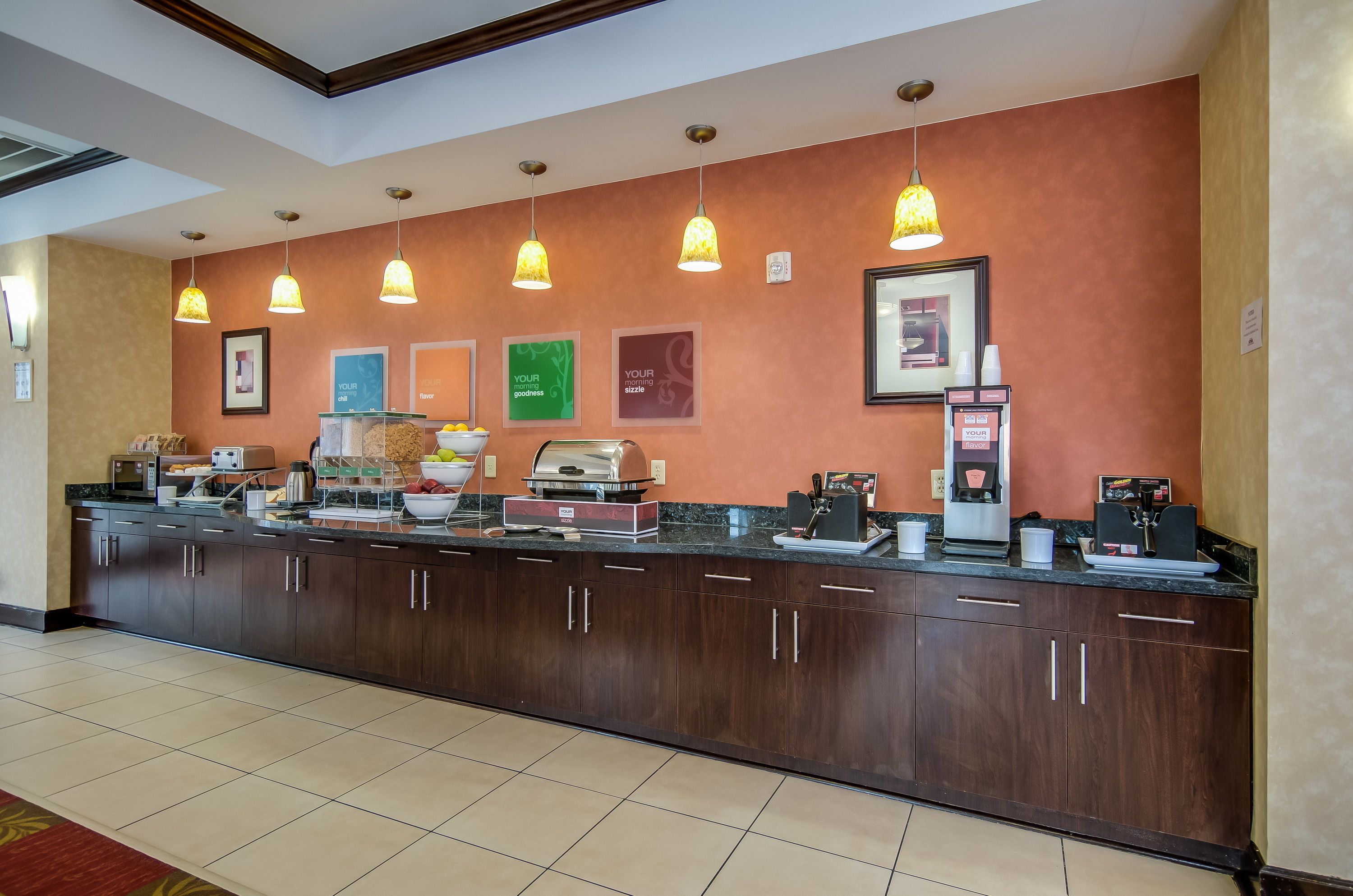 A hotel reception area with a long counter, multiple coffee machines, and a variety of breakfast items.
