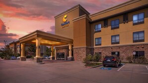 Un hotel con un letrero llamativo, un acceso cubierto y un área de estacionamiento.