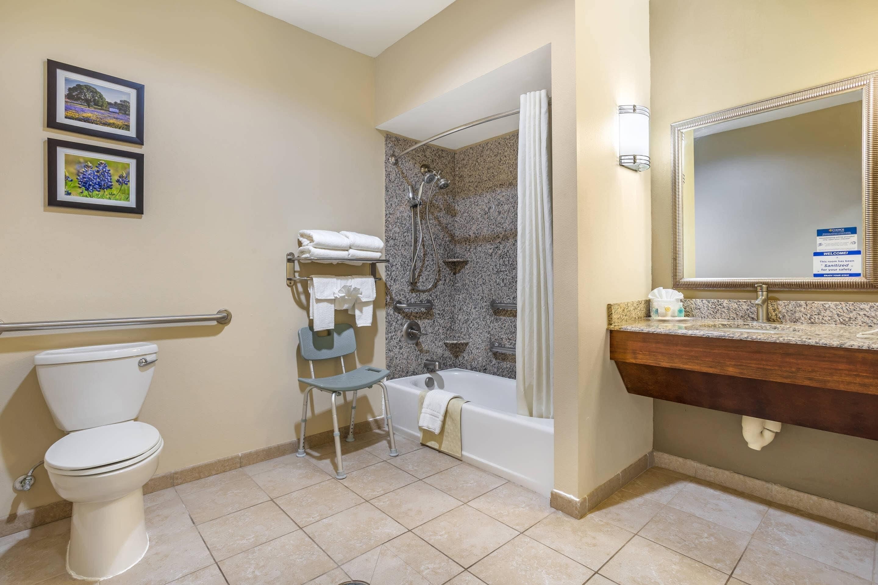 A bathroom with a toilet, a shower, a bathtub, a sink, and a chair.