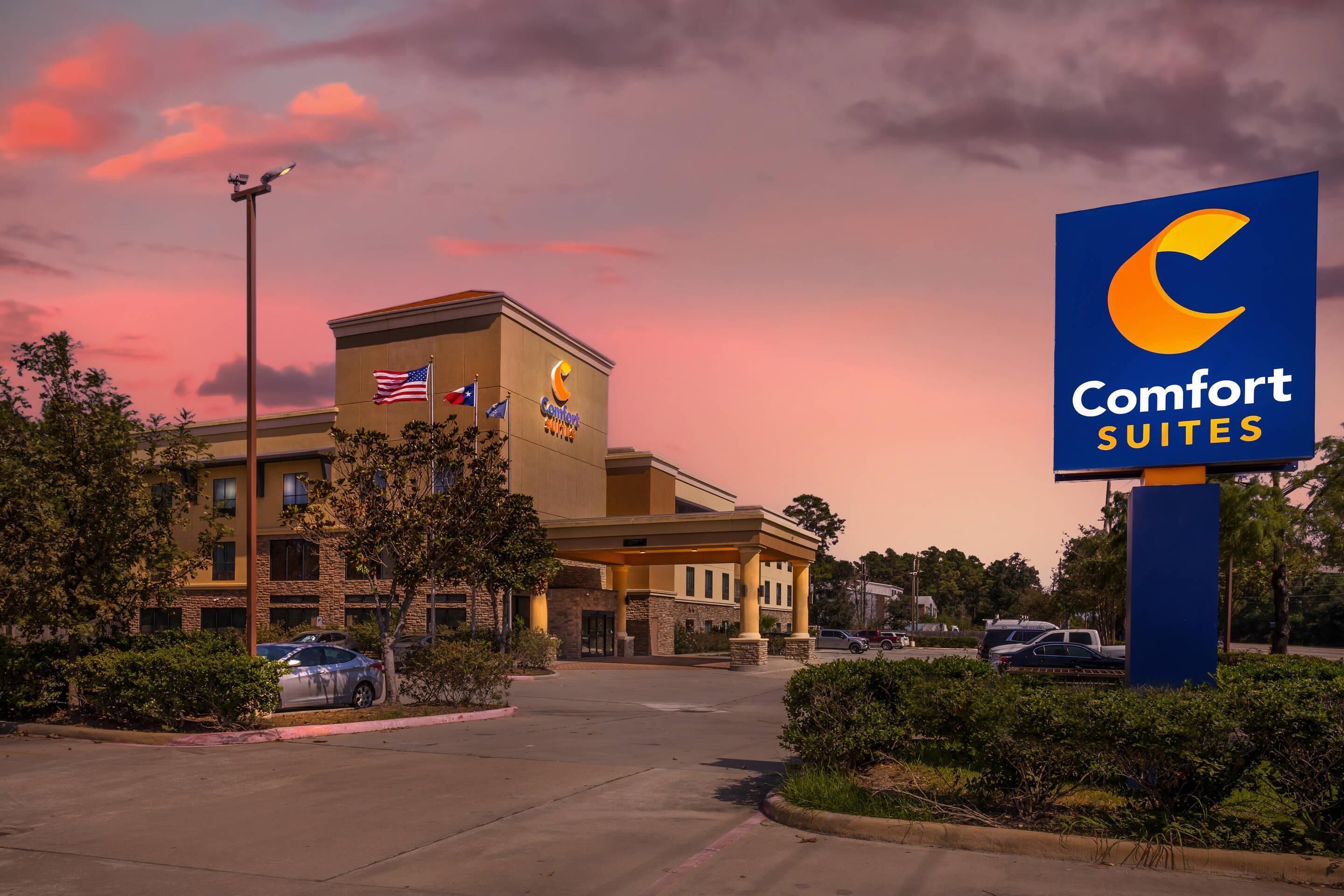 A Comfort Suites hotel with a covered entrance, American flags, and a parking lot.