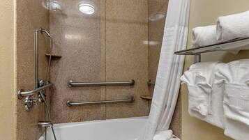 Ein Badezimmer mit Badewanne, Haltegriffen, Duschkopf und Handtuchhalter.