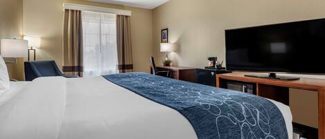 A hotel room with a large bed, a flat-screen TV, a desk, and a chair.
