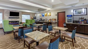 A hotel lobby with multiple seating areas, a kitchen area, and a television mounted on the wall. - Comfort Inn & Suites Paris (Paris)