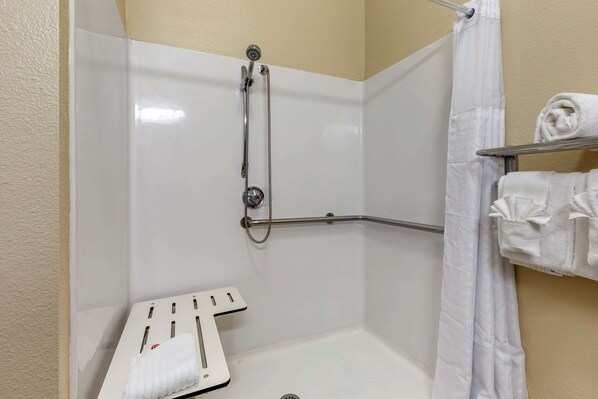 A shower area with a grab bar, a towel rack, and a showerhead.
