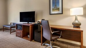 A hotel room with a wooden desk, a television, a microwave, a chair, and a lamp. - Comfort Inn & Suites Paris (Paris)