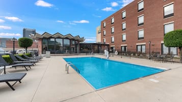 A swimming pool with lounge chairs and a building with a Holiday Inn Express sign.