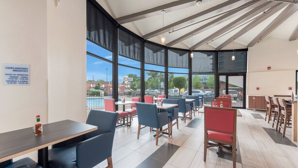 A modern restaurant with large windows, a complimentary breakfast sign, and a view of the parking area. - Holiday Inn Express Columbus Downtown by IHG (Columbus)