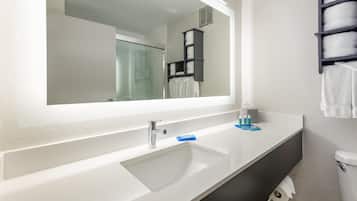 A modern bathroom with a white sink, a large mirror, and a towel rack.