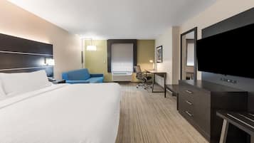 Quarto de hotel com uma cama grande, escrivaninha, cadeira, televisão e guarda-roupa.