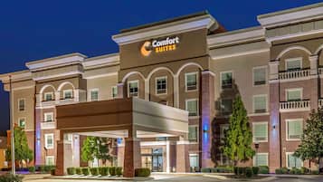 A Comfort Suites hotel with a modern facade, multiple balconies, and a well-lit entrance.
