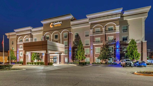 Un hôtel Comfort Suites avec une façade en briques, de nombreux balcons et une entrée abritée.