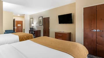A hotel room with two beds, a desk, a chair, a TV, and a wardrobe.