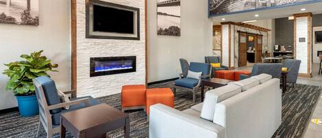 A hotel lobby with a fireplace, seating area, and a large mural.