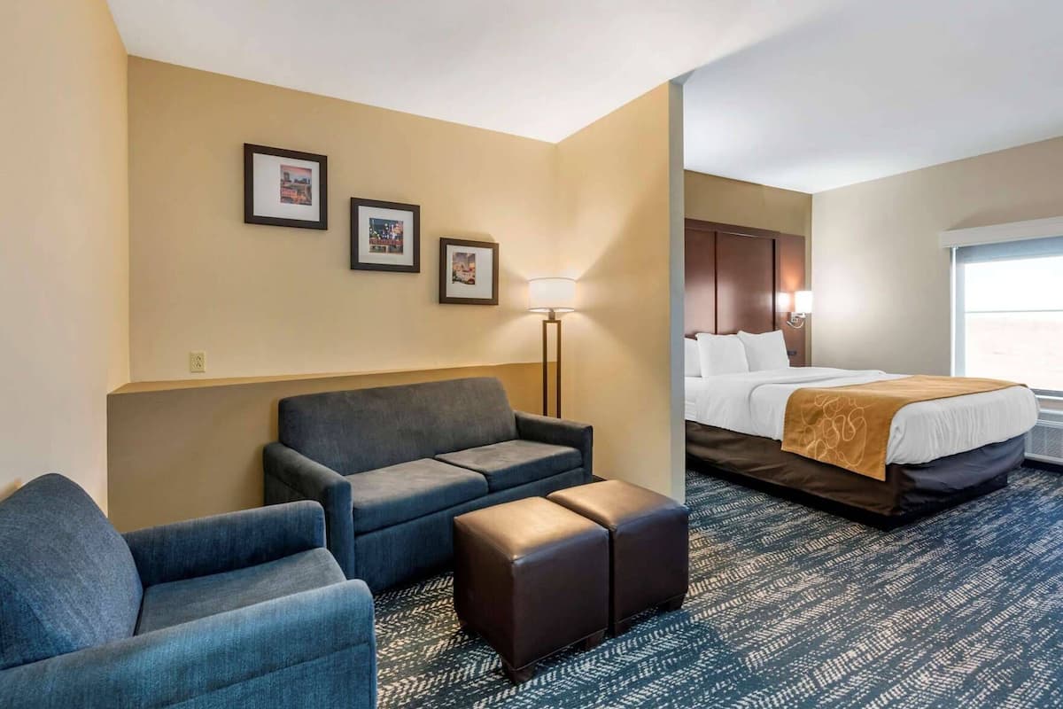 Habitación de hotel con sofá, reposapiés, cama y lámpara.