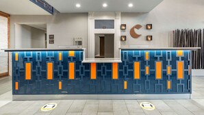 Un comptoir d’accueil au motif géométrique et au design moderne. Un panneau au sol indique les mesures de distanciation sociale.