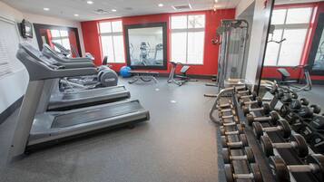 Un gimnasio con cintas de correr, máquinas de pesas y mancuernas.