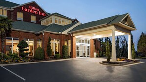 Un hôtel Hilton Garden Inn avec une façade en briques, de grandes fenêtres et une entrée abritée.