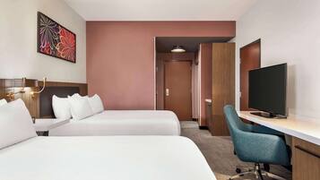 Camera d'albergo con due letti, una scrivania con sedia, televisione e un quadro appeso al muro.