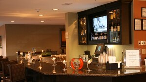 Una zona de bar con mostrador, sillas y una pantalla de televisión.