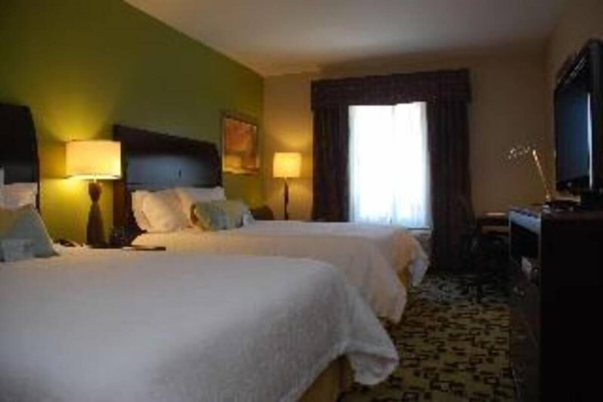 Habitación de hotel con dos camas, televisión y escritorio.