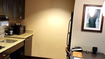 A compact kitchen with dark cabinets, a granite countertop, and a dining area with a table and chairs.