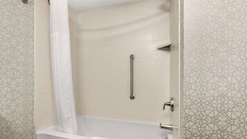 Un baño moderno con bañera, cortina de ducha, barra de apoyo y azulejos estampados.