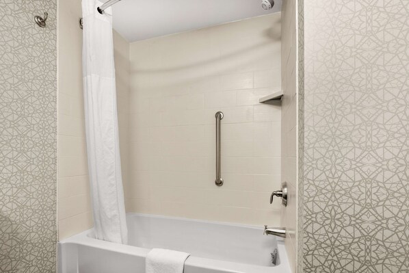 A modern bathroom with a bathtub, a shower curtain, a grab bar, and patterned tiles.