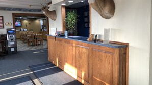A reception area with a wooden counter, mounted deer heads, a potted plant, and a reception desk. - Amber Inn Motel Le Mars (Le Mars)