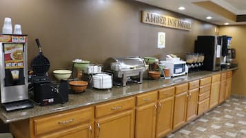 A breakfast bar with a waffle maker, coffee machine, and various bowls and containers.