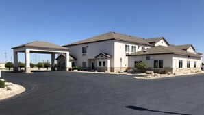 A two-story building with a covered entrance and a clear driveway. - Lea County Inn (Hobbs)