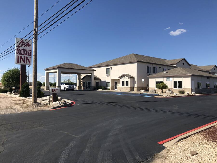A motel with a covered parking area and a sign indicating the name.