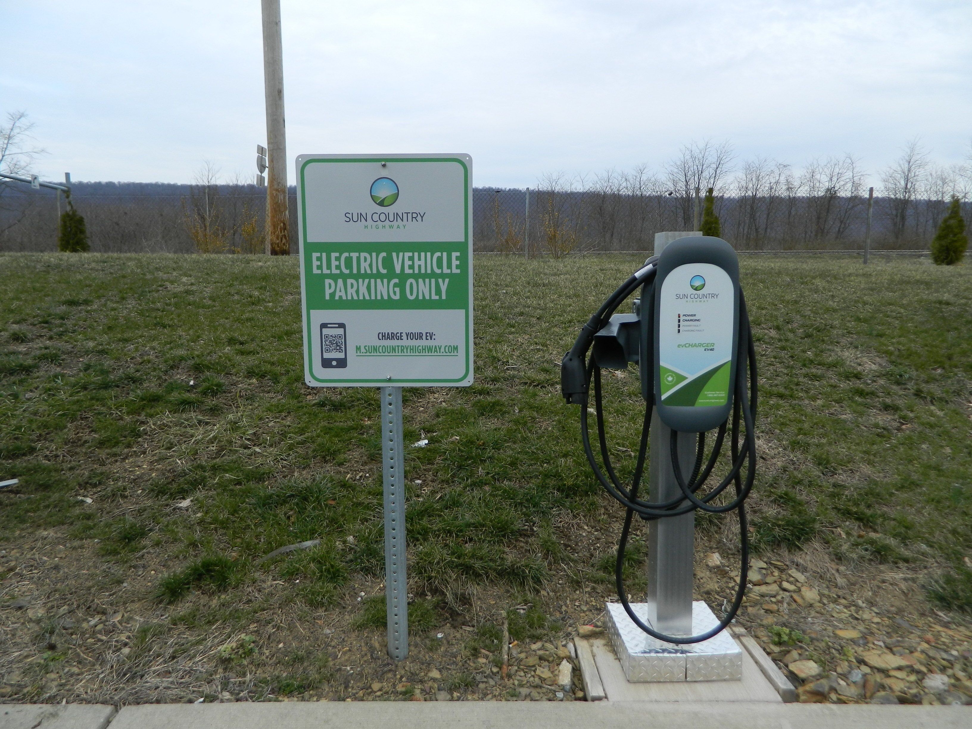 Señal para estacionamiento de vehículos eléctricos Sun Country Highway, con estación de carga.