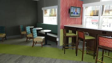 Un restaurante con barra, mesas con cabinas y sillas altas.
