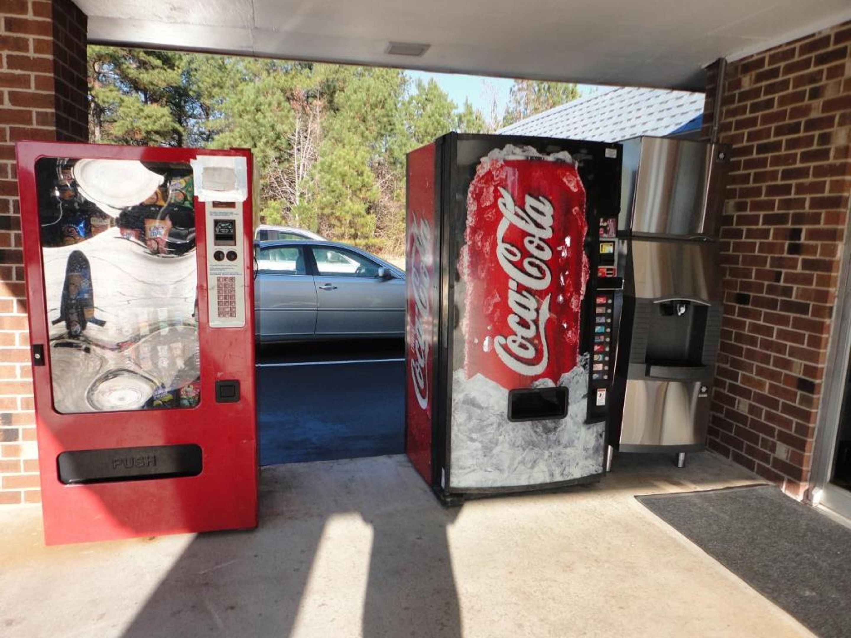 Máquina automática de Coca-Cola e máquina de venda de bilhetes numa garagem.