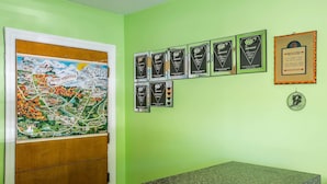 A room with a green wall, a wooden door with a map, and several framed certificates. - Rodeway Inn Lincoln I-93 (Lincoln)
