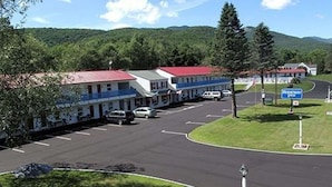 A motel with a red roof, a parking lot, and a sign for the Rocky Mountain Inn. - Rodeway Inn Lincoln I-93 (Lincoln)