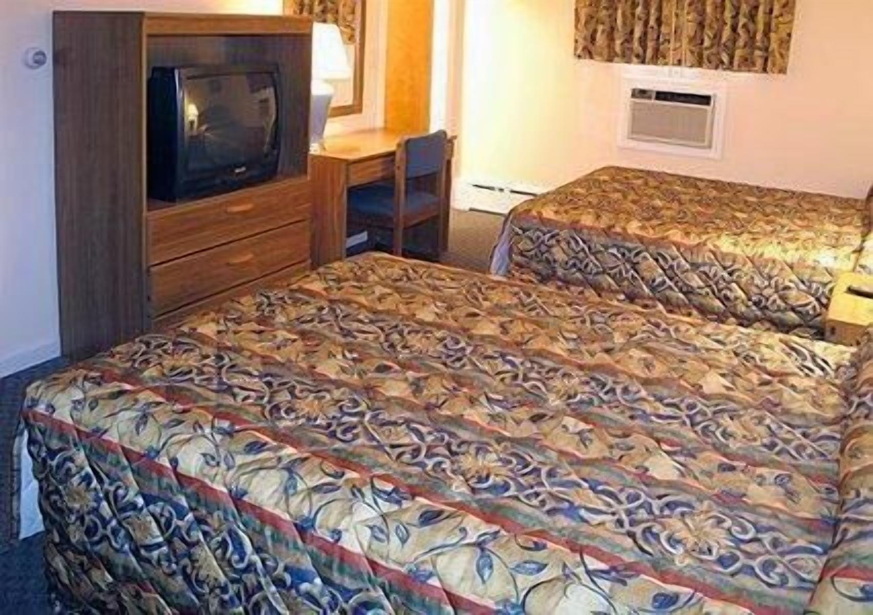 Une chambre d’hôtel avec deux lits, une télévision, un bureau et une chaise.