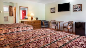 A hotel room with two beds, a desk, a chair, a television, and a refrigerator. - Rodeway Inn Lincoln I-93 (Lincoln)