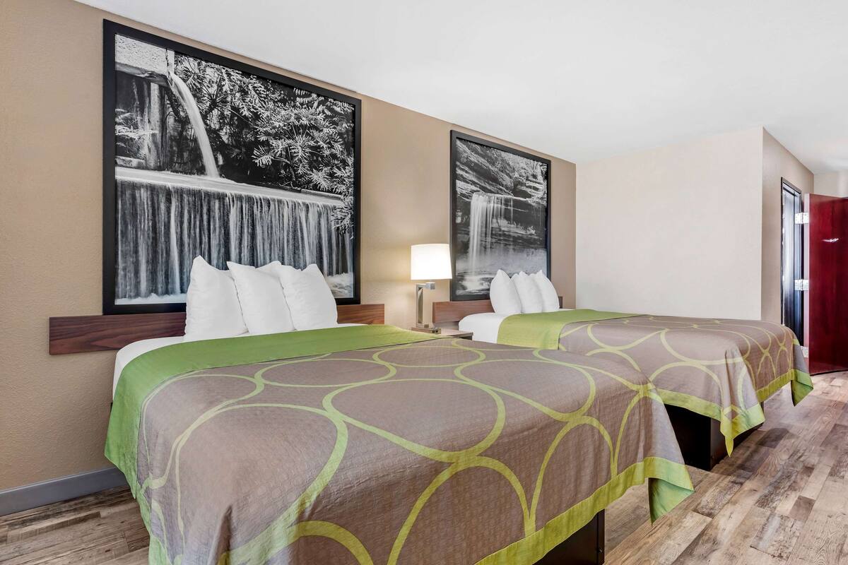 Quarto de hotel com duas camas, uma janela grande e vista para uma cascata.