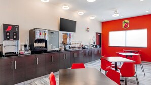 Ein modernes Café mit roter Wand, einem Flachbildfernseher und einer Kaffeemaschine.