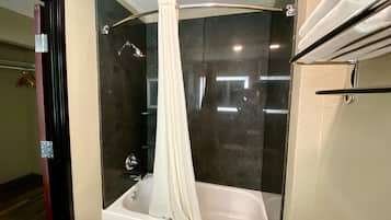 Un baño con ducha envuelta en vidrio, una bañera blanca y un perchero para toallas.