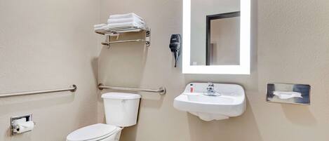 A bathroom with a toilet, a sink, a towel rack, a hand dryer, and a mirror.