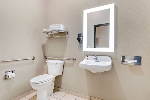 Une salle de bain équipée de toilettes, d’un lavabo, d’un porte-serviettes, d’un sèche-mains et d’un miroir.