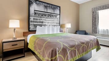 A hotel room with a bed, two bedside tables with lamps, a large framed picture on the wall, and an air conditioning unit.