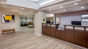 A modern reception area with a wooden reception desk, a bench, and a wall-mounted sign. - Residence Inn by Marriott Birmingham Downtown at UAB (Birmingham)