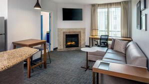 A modern living room with a fireplace, a flat-screen TV, a sofa, a coffee table, and a desk. - Residence Inn by Marriott Birmingham Downtown at UAB (Birmingham)