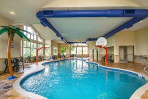 An indoor swimming pool with a basketball hoop, lounge chairs, and a palm tree decoration. - Sleep Inn & Suites Madison - Monona (Madison)