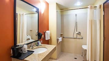 A bathroom with a sink, mirror, shower, and toilet.