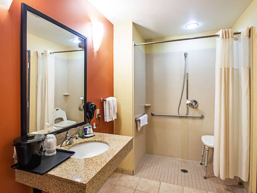 A bathroom with a sink, mirror, shower, and toilet.